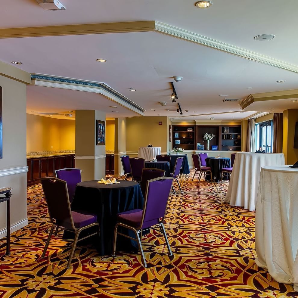 A meeting room with tables, chairs, and a patterned carpet.