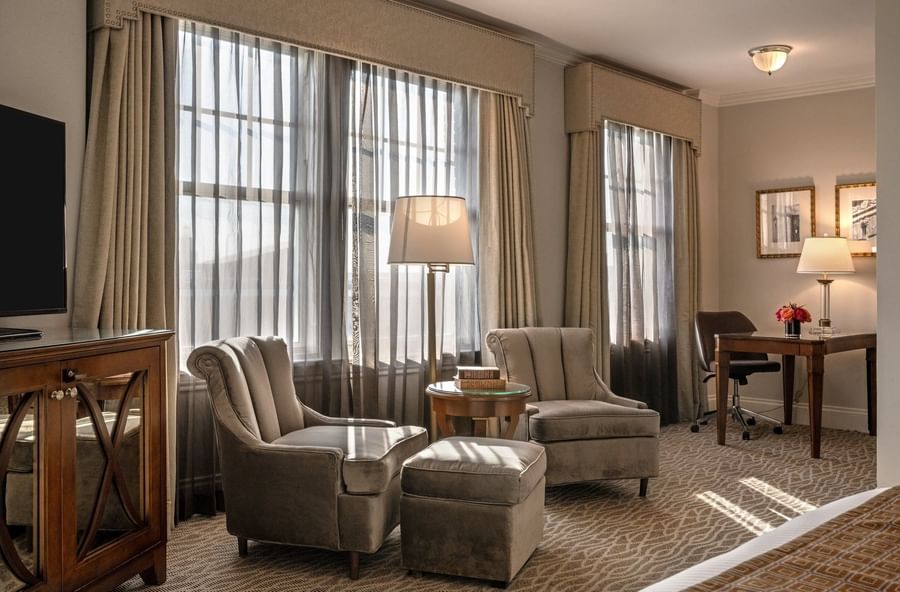Deluxe King with Two plush armchairs by a round table under a tall lamp in Deulux king at Warwick Melrose Dallas