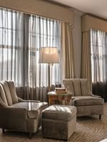 Deluxe Double with Two plush armchairs by a round table under a tall lamp in a sunny guest room at Warwick Melrose Dallas