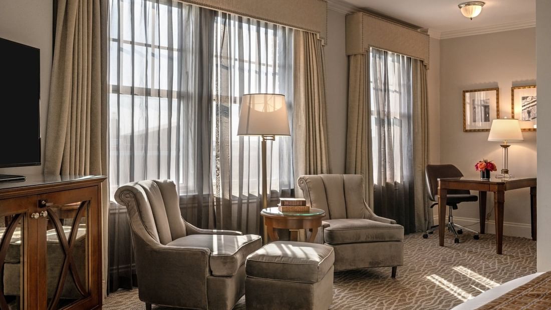 Deluxe King with Two plush armchairs by a round table under a tall lamp in Deluxe King at Warwick Melrose Dallas