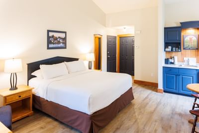 King Cottage No Water View with a large bed by nightstands near a blue kitchenette area at Rodd Brudenell River Resort
