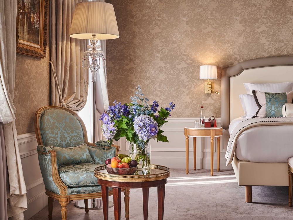 Bed with side table under a wall lamp near couch in Prestige Suite – Rue de la Paix View at Hotel Westminster Paris