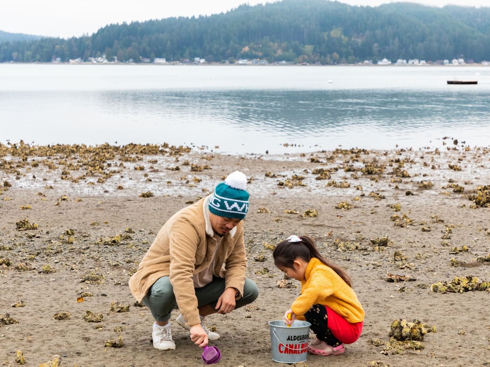Father and kid exploring the sandy area by the lake near Alderbrook Resort & Spa