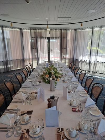 Wedding setup with a long table and a centerpiece of flowers in the Park Room at Amora Herencia Riverwalk Melbourne