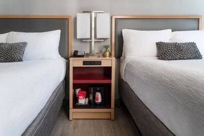 Accessible Double with two white beds near a wooden nightstand, twin lamp, & coffee maker shelf at Hotel Saint Clair