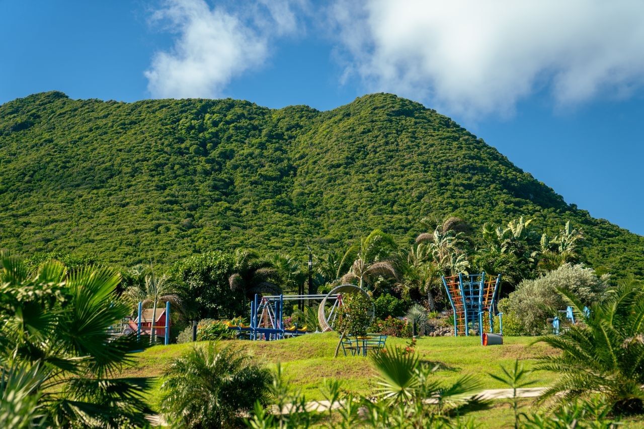 Childrens outdoor playground equipment set carefully on a lush green lawn near the large mountain at Golden Rock Resort