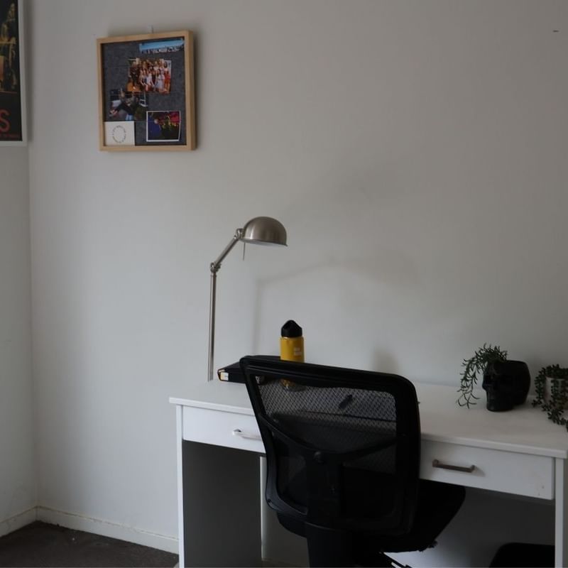 Simple white desk with chair, lamp, and small plant at La Trobe University Regional Housing.