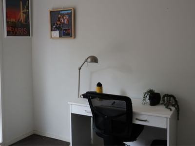 Simple white desk with chair, lamp, and small plant at La Trobe University Regional Housing.