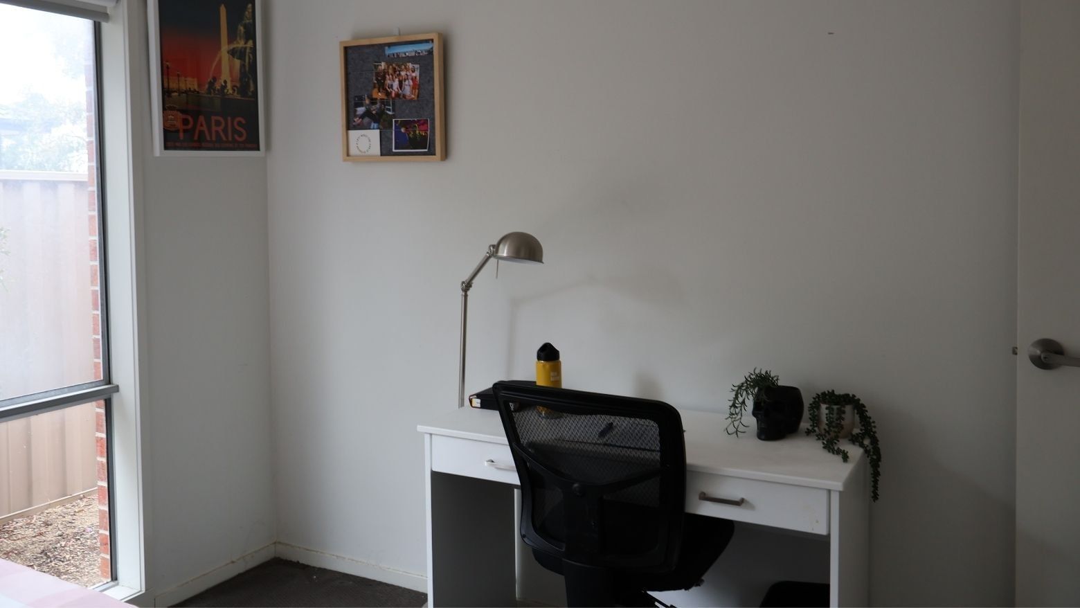 Simple white desk with chair, lamp, and small plant at La Trobe University Regional Housing.