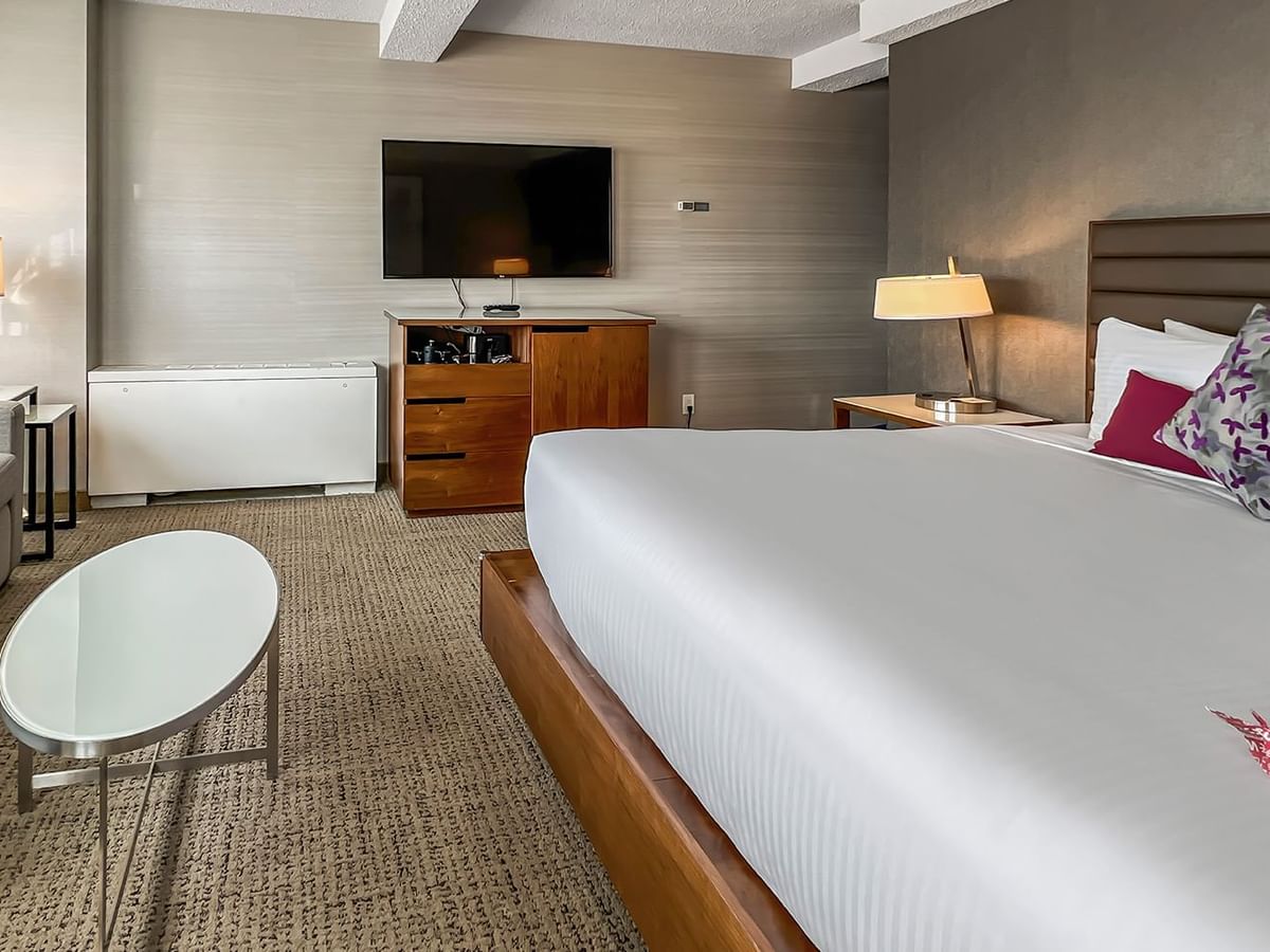 Hotel bedroom with bed, couch, TV, and table