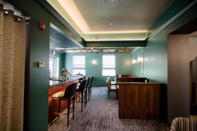 Modern bar lounge with sleek high chairs facing the counter and a stained-glass ceiling at La Tourelle Hotel and Spa