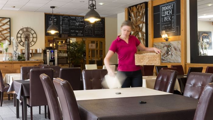 A waitress cleaning a dining table at Hotel du Faucigny