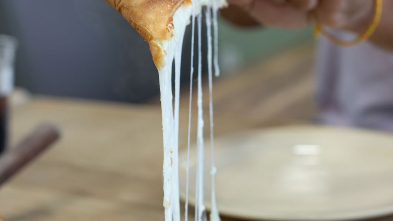 Close-up of cheesy pizza pull in Bruno’s Pizza at Watersound Inn