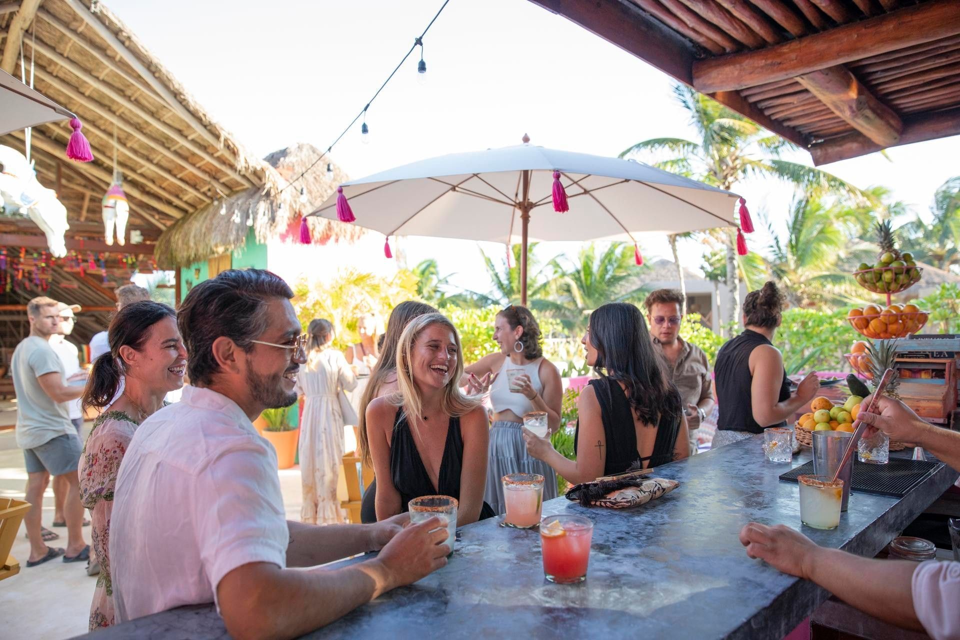 Friends laughing over colorful margaritas at La Zebra's open-air bar in Tulum