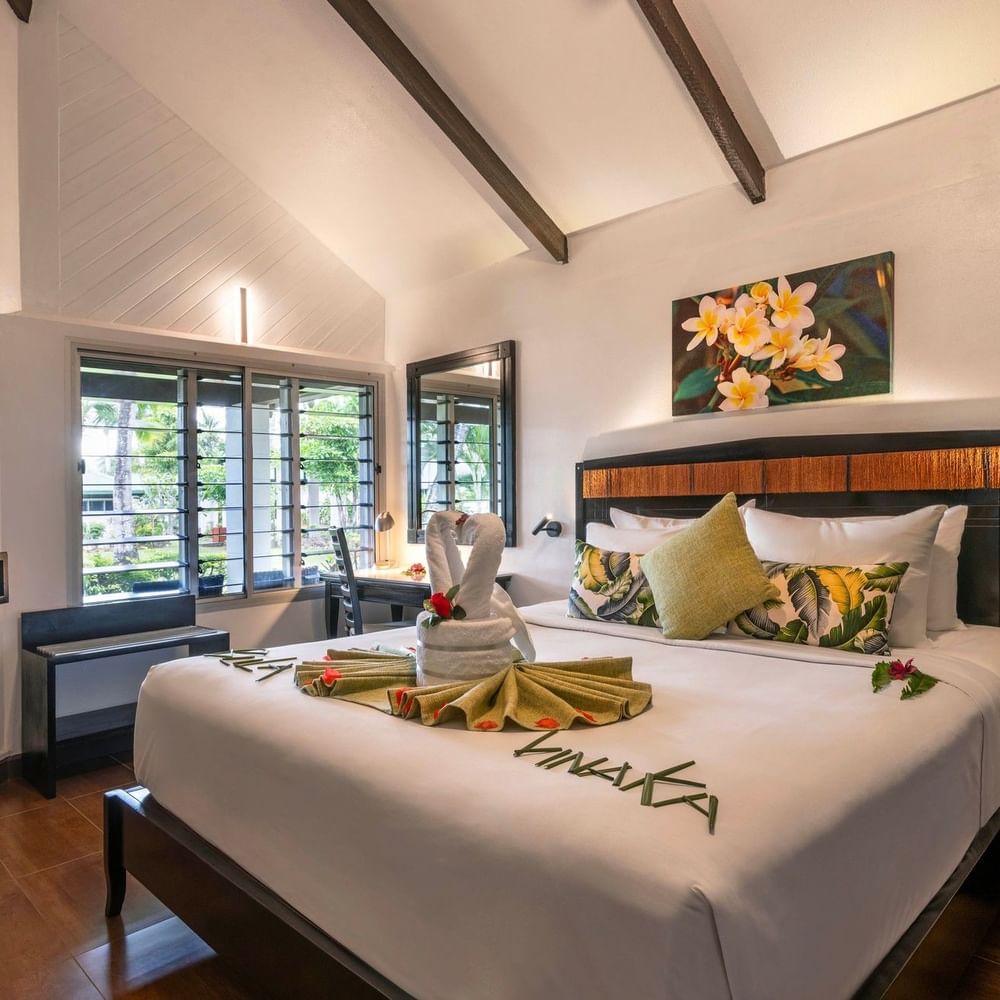 Cozy bedroom with white bedding and tropical decor in One Bedroom Villa at Tokatoka Resort Nadi.
