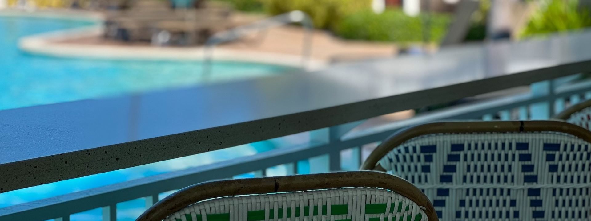 Woven chairs by a sleek counter surrounding a pool in Chickcharnie's Pizzeria & Grille at Warwick Paradise Island Bahamas