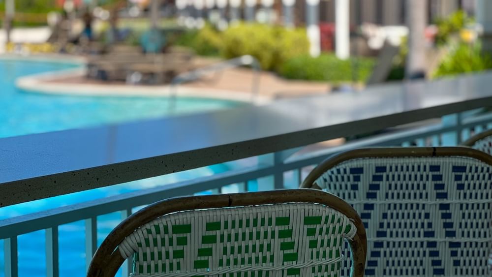 Woven chairs by a sleek counter surrounding a pool in Chickcharnie's Pizzeria & Grille at Warwick Paradise Island Bahamas