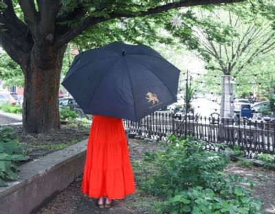 Rear view of a girl holding an umbrella with Eliot Hotel's sign