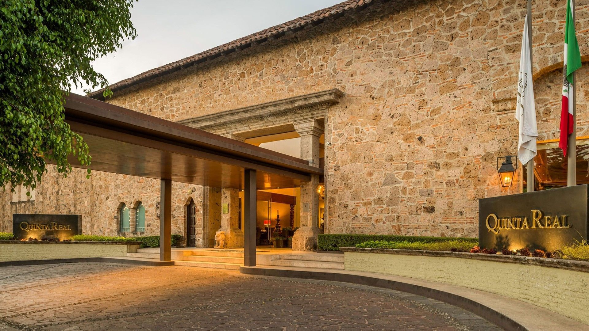 Stone facade entrance with a modern canopy and warm lighting at Quinta Real Guadalajara