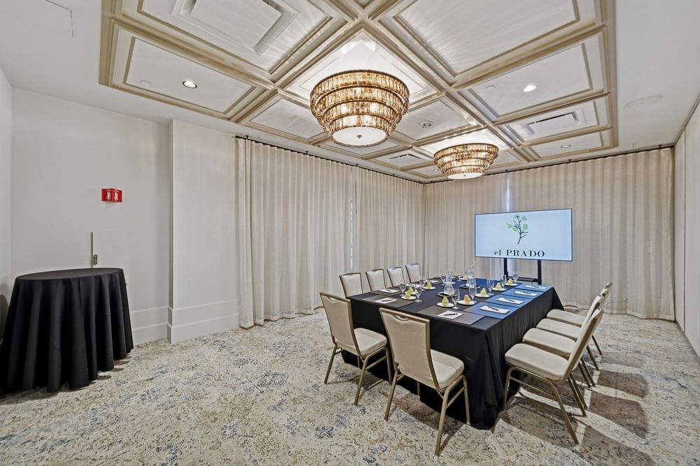 meeting room set up at el PRADO with a screen at the end of the table reading el PRADO with a yellow flower