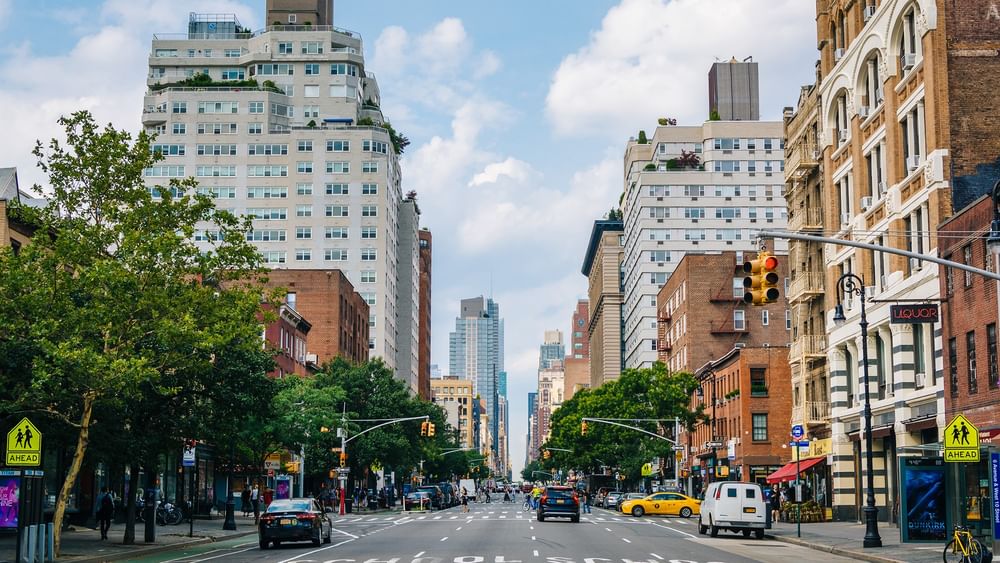 A busy New York City street with cars, pedestrians, and high-rise buildings.