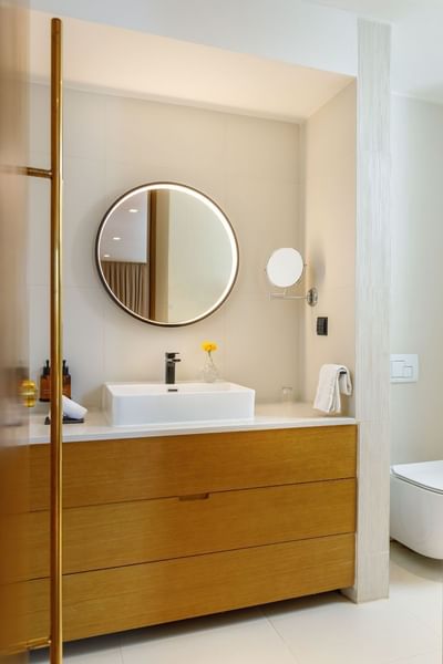 Superior Suites Bathroom with wooden vanity, basin and round mirror at The Terraces Resort & Spa