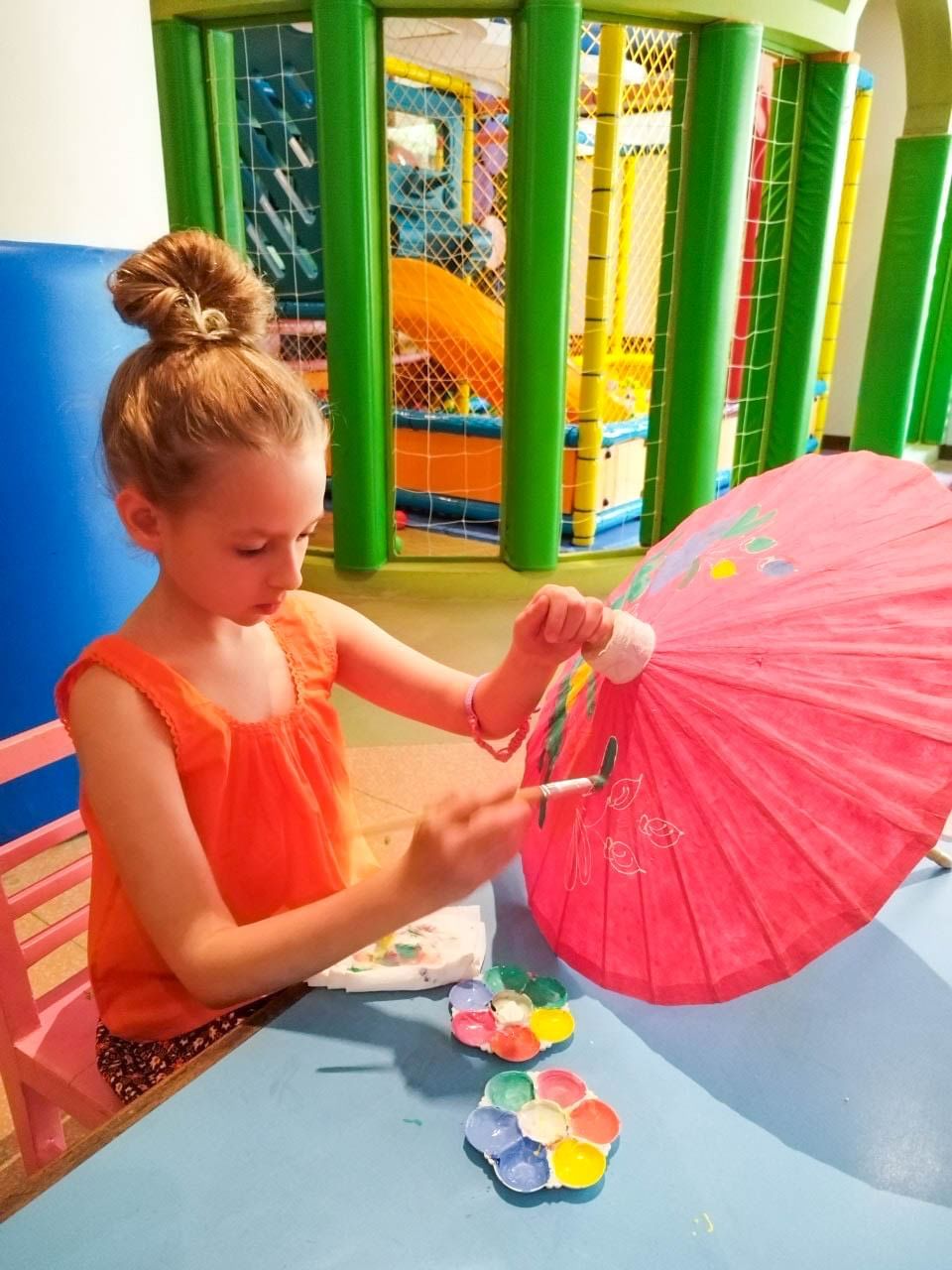 A girl, wearing a Thai traditional costume, is painting the umbrella at kids club at Paradox Resort Phuket