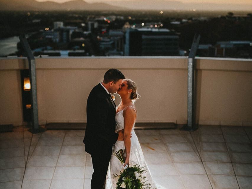 Wedded couple kissing on a balcony at Grand Chancellor Townsville