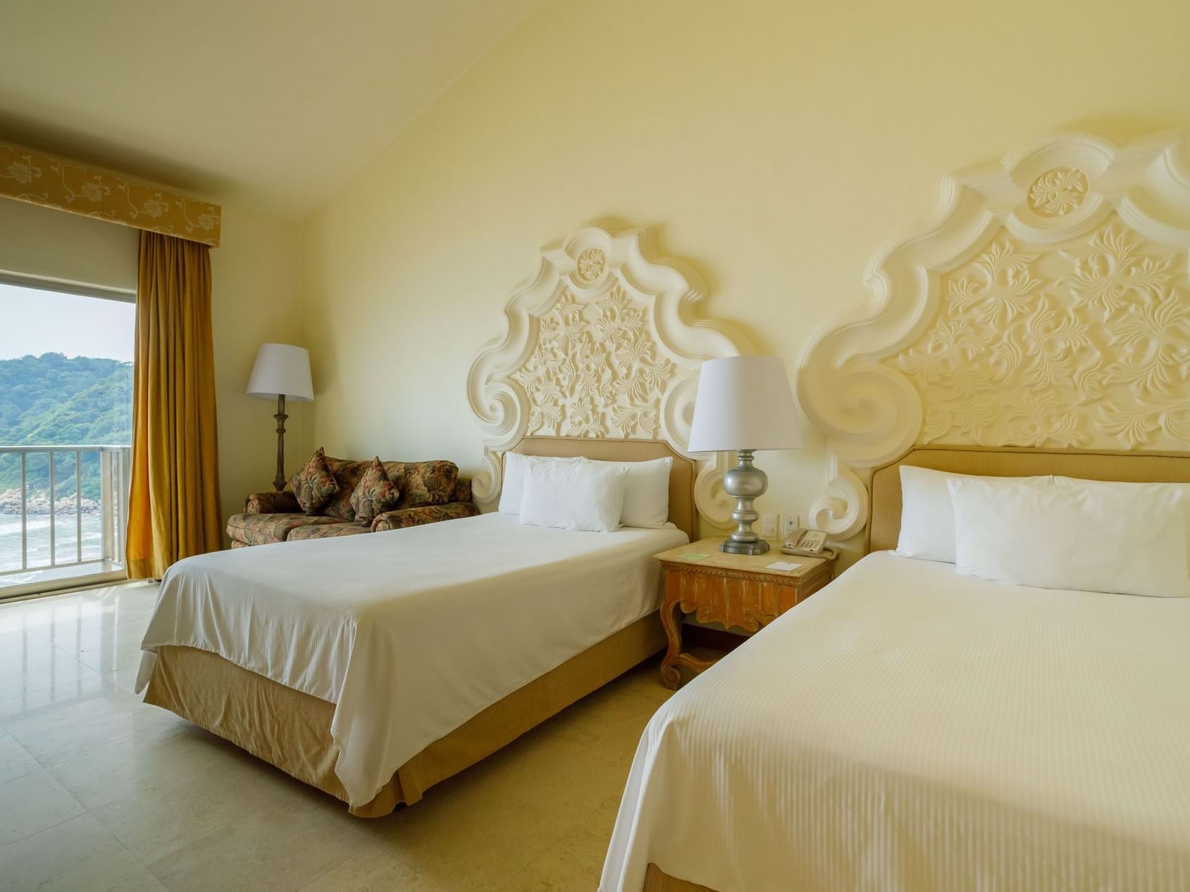 2 Double Master Suite with two beds, ornate headboards, and a view of the lush coastline at Quinta Real Acapulco