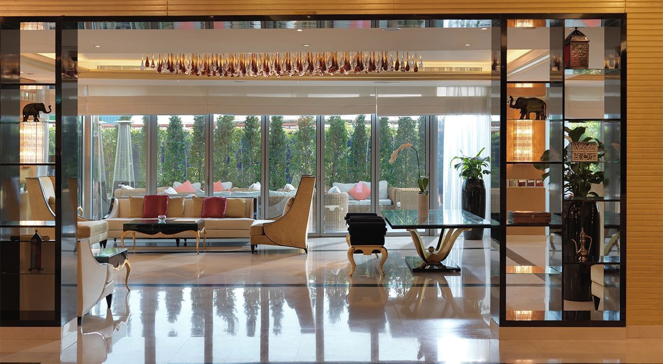 Lobby area with furniture, glass tables, and large windows overlooking greenery at DAMAC Maison Mall Street