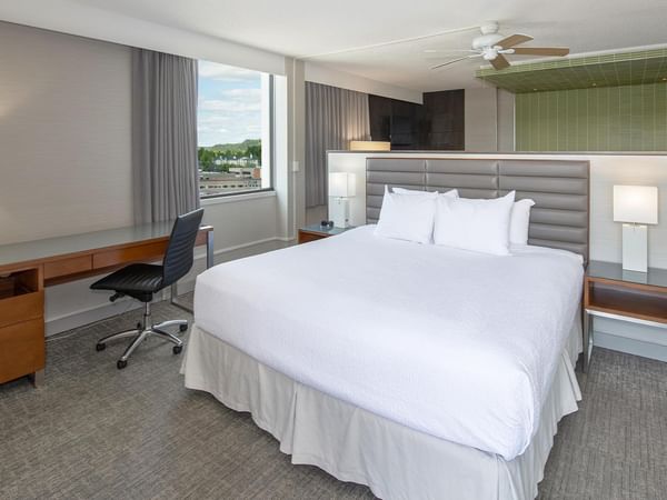 Modern junior suite with king bed, work desk, city views, and green tiled bathroom at Coast Prince George Hotel