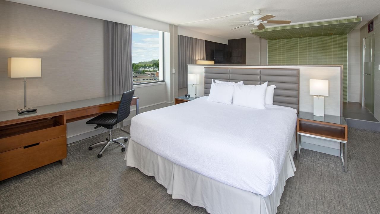 Modern junior suite with king bed, work desk, city views, and green tiled bathroom at Coast Prince George Hotel