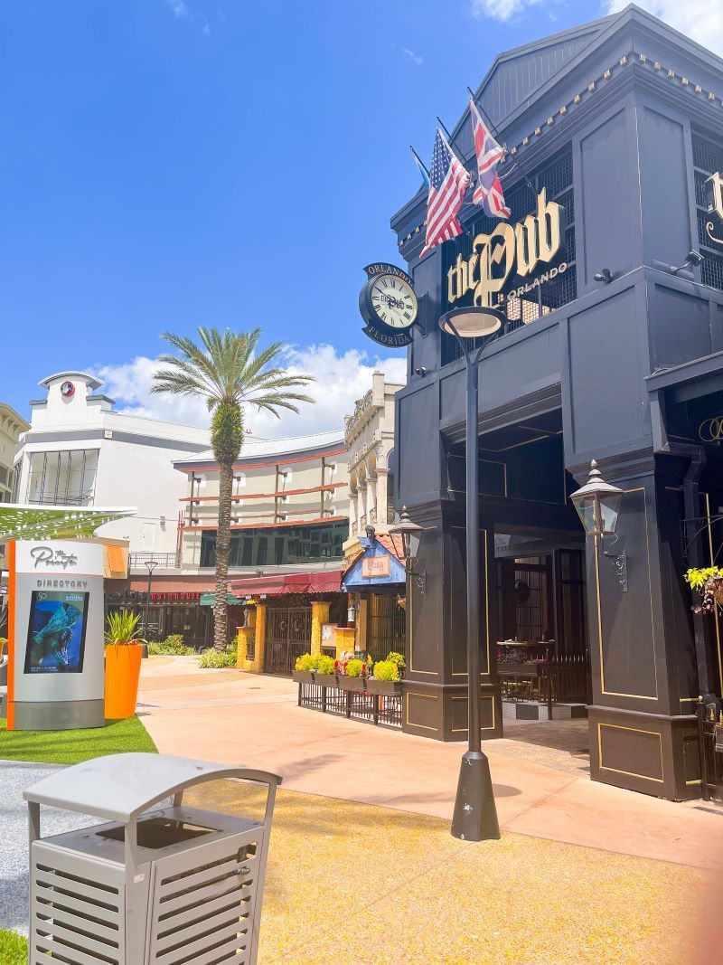 An image of a shopping strip with a dark grey british pub named the PUB Orlando. 