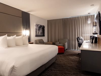 Hotel room with bed, seating area, desk, and TV at Carriage House Hotel & Conference Centre