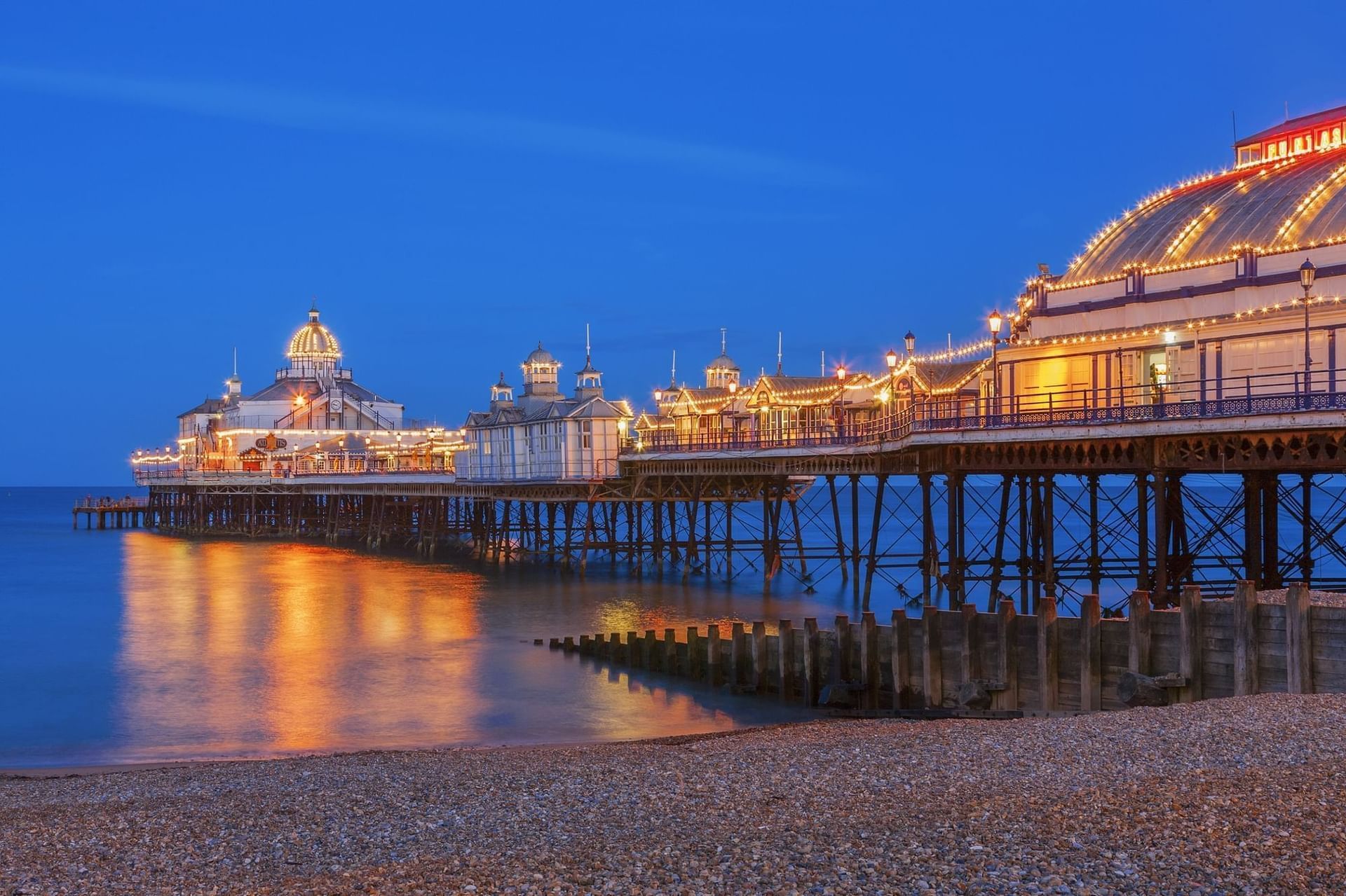 Illuminated pier at dusk with reflections in water at The View Hotel Eastbourne