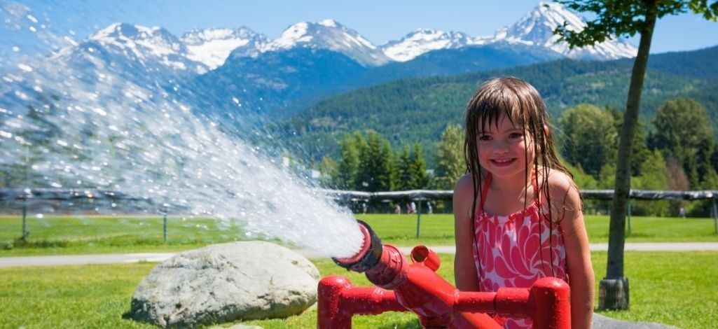 Child playing at a water feature with Whistler mountain views