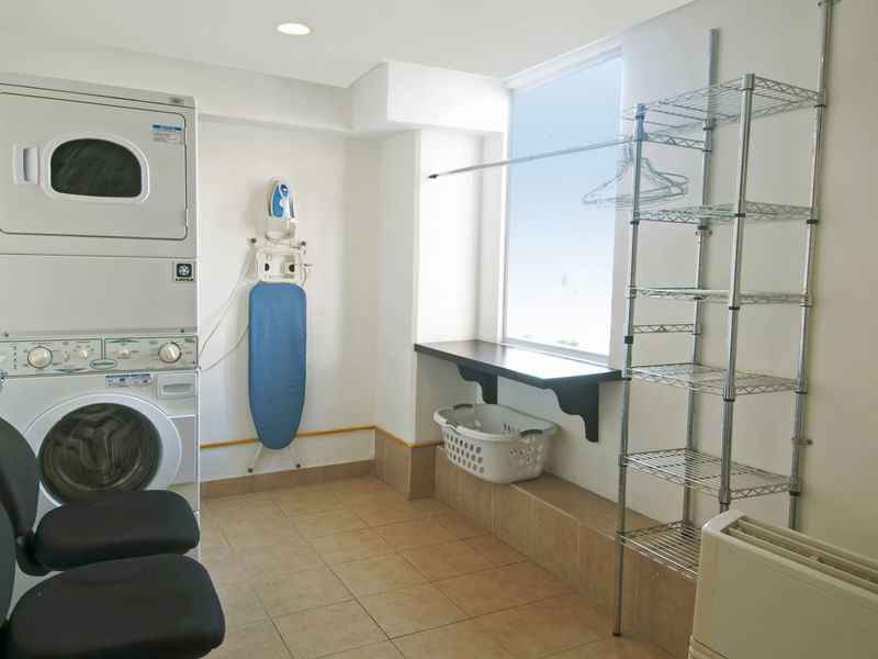 Laundry with ironing center arranged with racks and washing machines at One Hotels