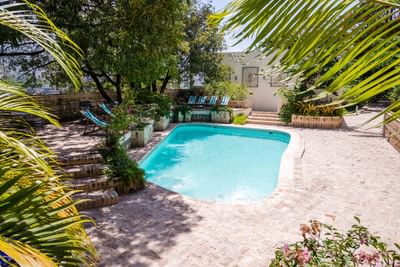 Turquoise pool by striped lounge chairs, framed under palm fronds and brick steps at Hotel Montana Haiti
