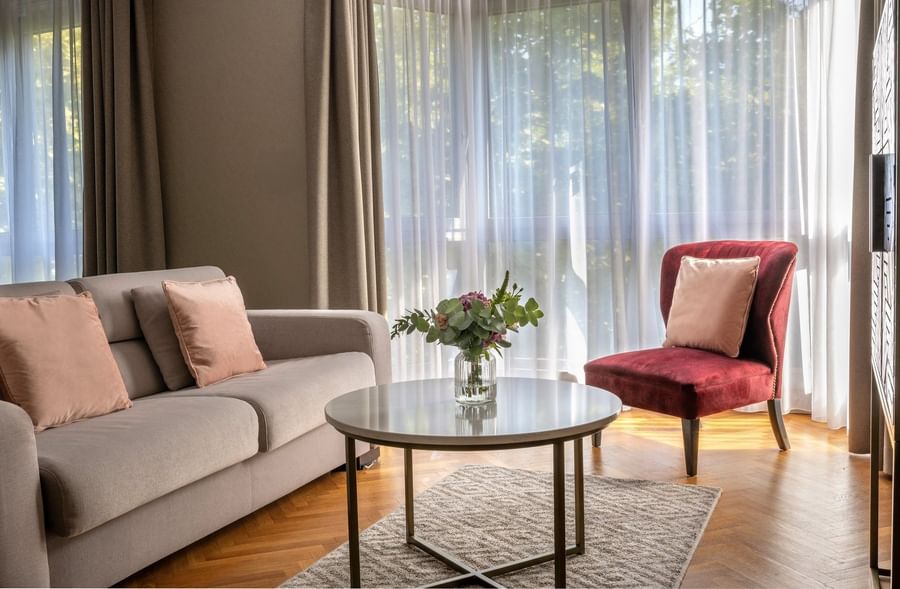 Living area with plush seating, wooden floors, and outdoor views in the Premium Suite at Warwick Reine Astrid - Lyon