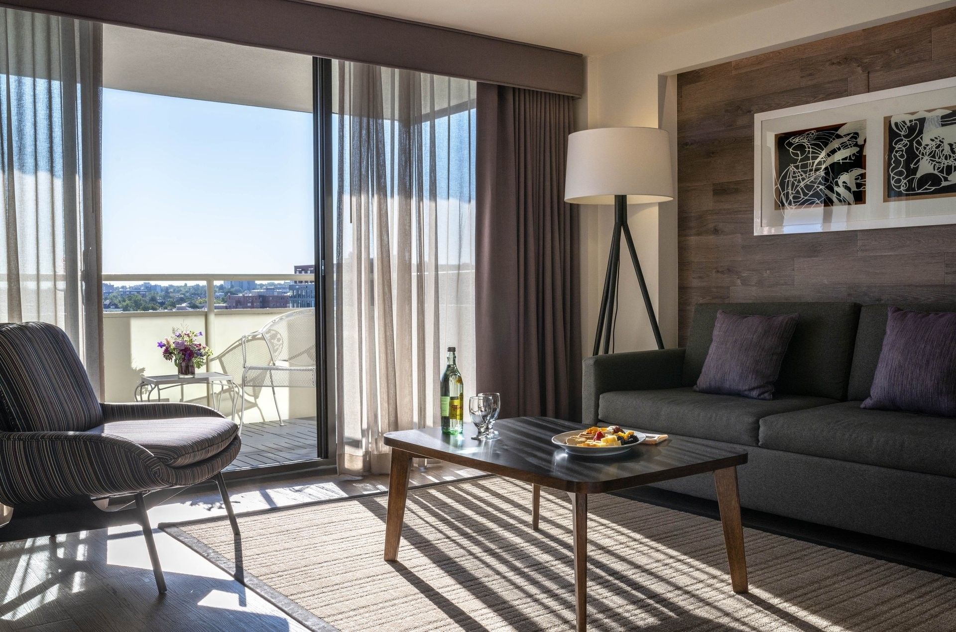White balcony chair by a glass door in a guestroom with a wood wall in Executive Suites at Warwick Denver