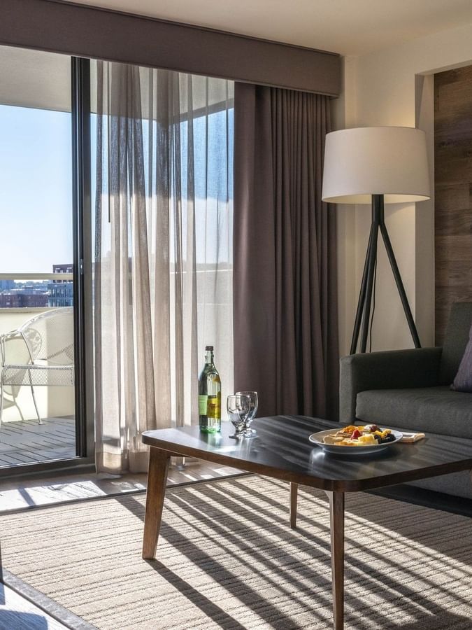 Sofa by a coffee table under framed art near a sunny balcony in Premier Suite at Warwick Denver