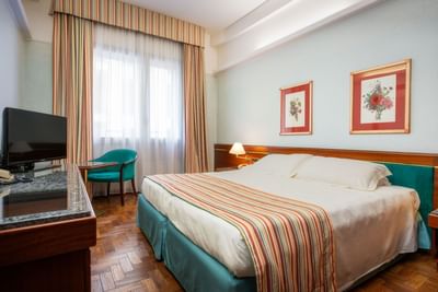 Cozy bed, TV, table with a chair & windows in Classic Room at Hotel Crivi's in Milan