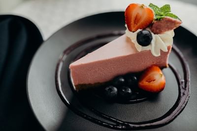 Slice of pink cheesecake topped with fresh strawberries and whipped cream served at The Boulevard Inn & Bistro