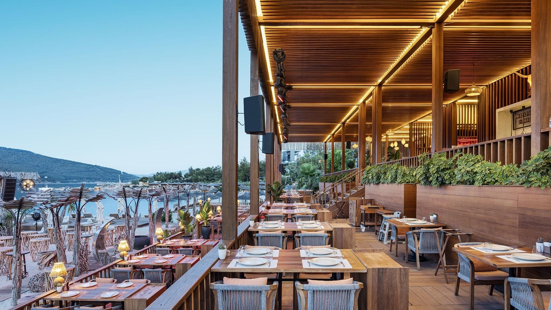 Beef Burger House with wooden tables, cushioned chairs, and a stunning view of the sea at Titanic Luxury Collection Bodrum