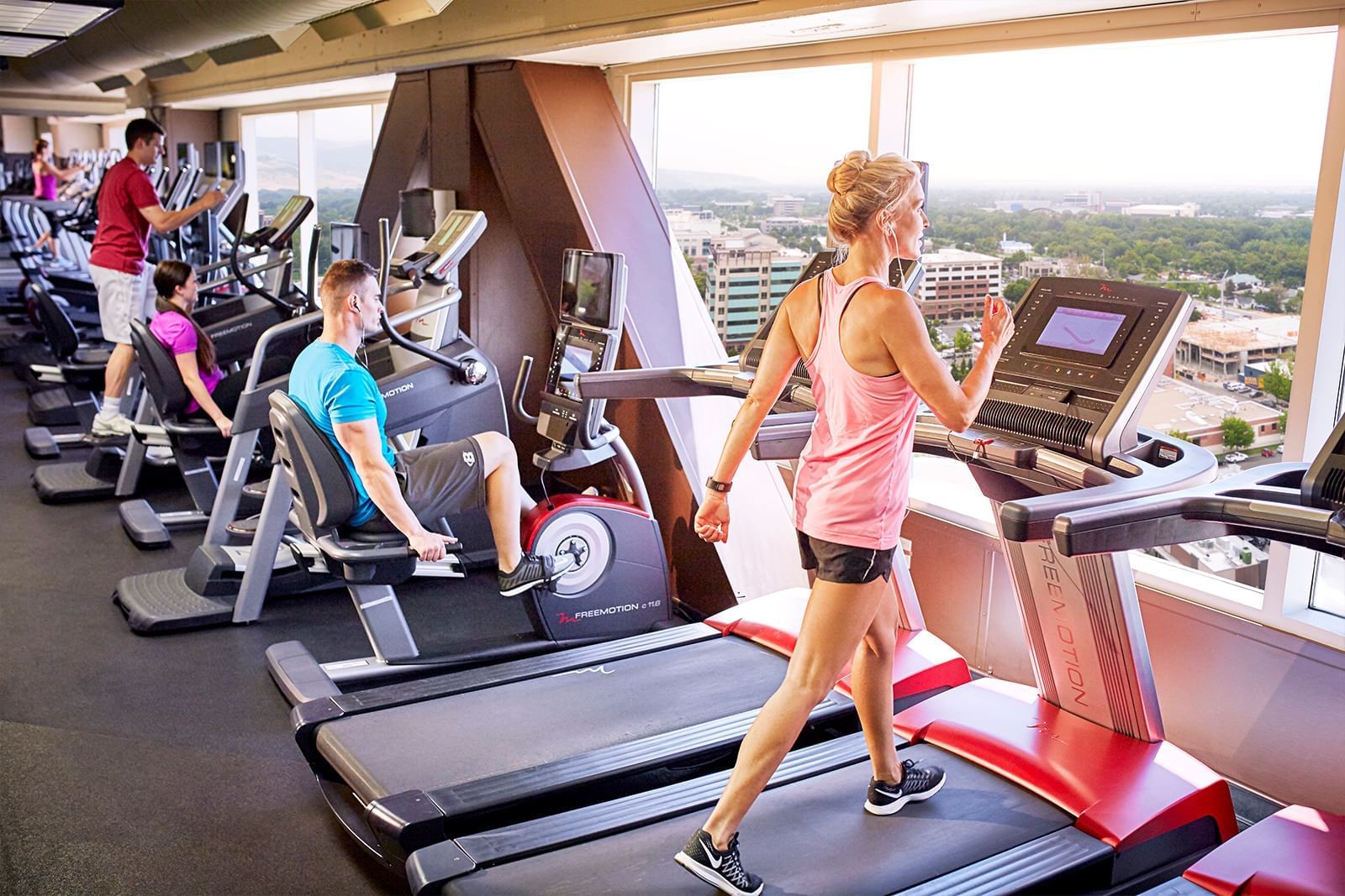 Men and women using workout equipment in the gym at Grove Hotel