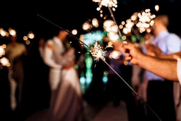 Bride and groom surrounded by their wedding guests holding sparklers at their New Years Eve wedding