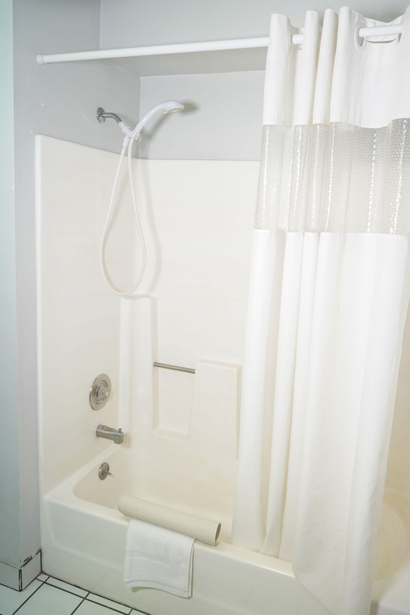 A clean and simple bathroom with a white bathtub and shower curtain.