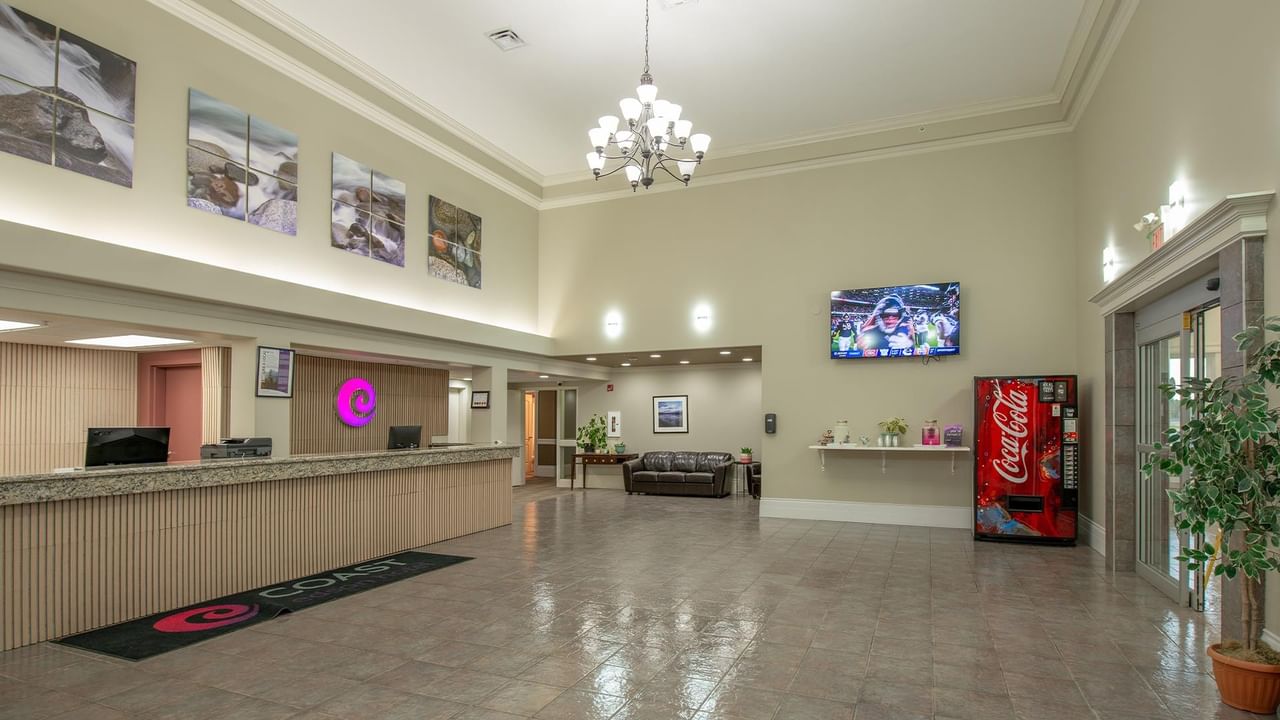 Spacious hotel lobby with reception desk, chandelier, seating area, and vending machine at Coast Edson Hotel