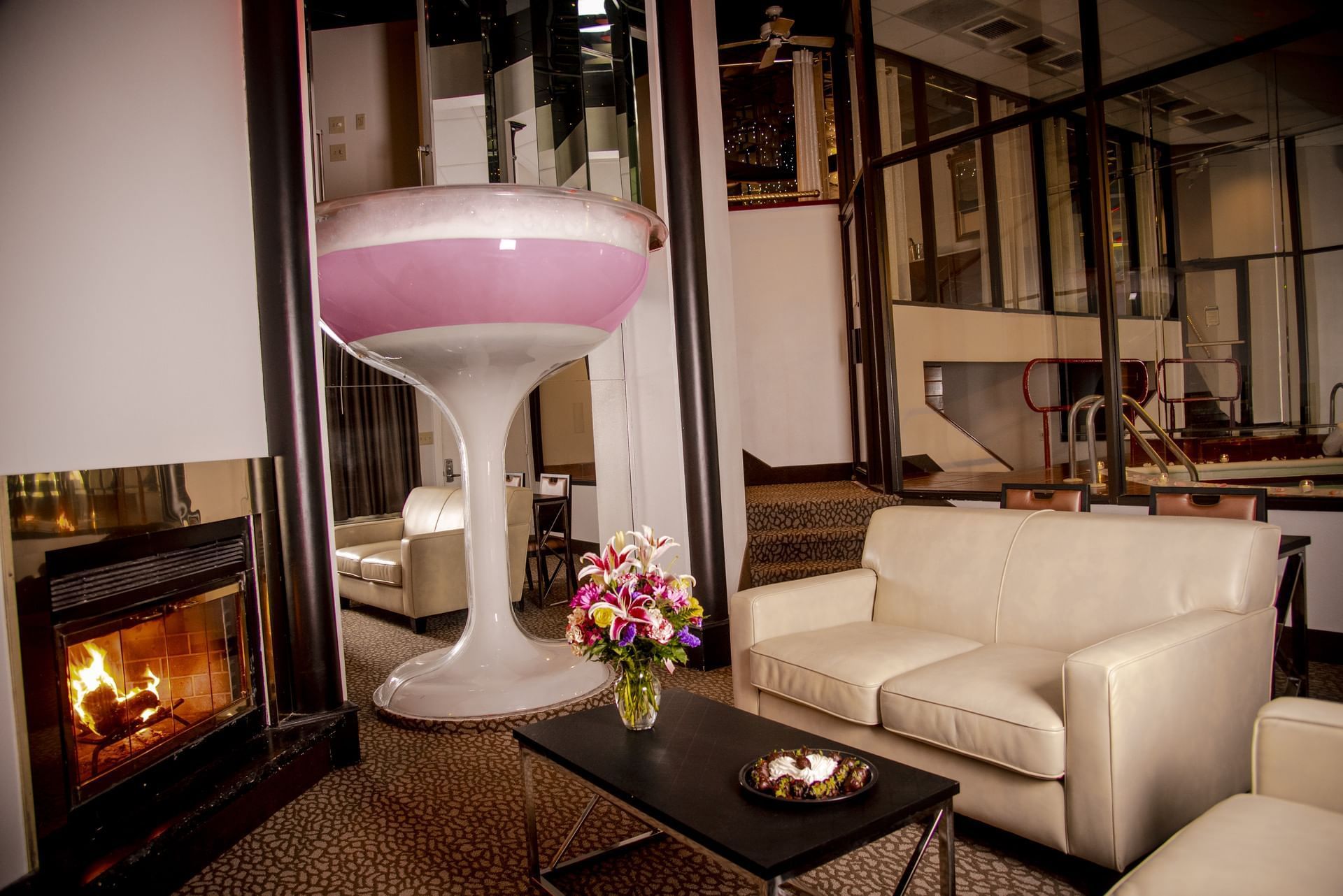 Lounge with a giant pink cocktail glass, plush sofas and a cozy fireplace in Champagne Tower Room at Cove Pocono Resorts