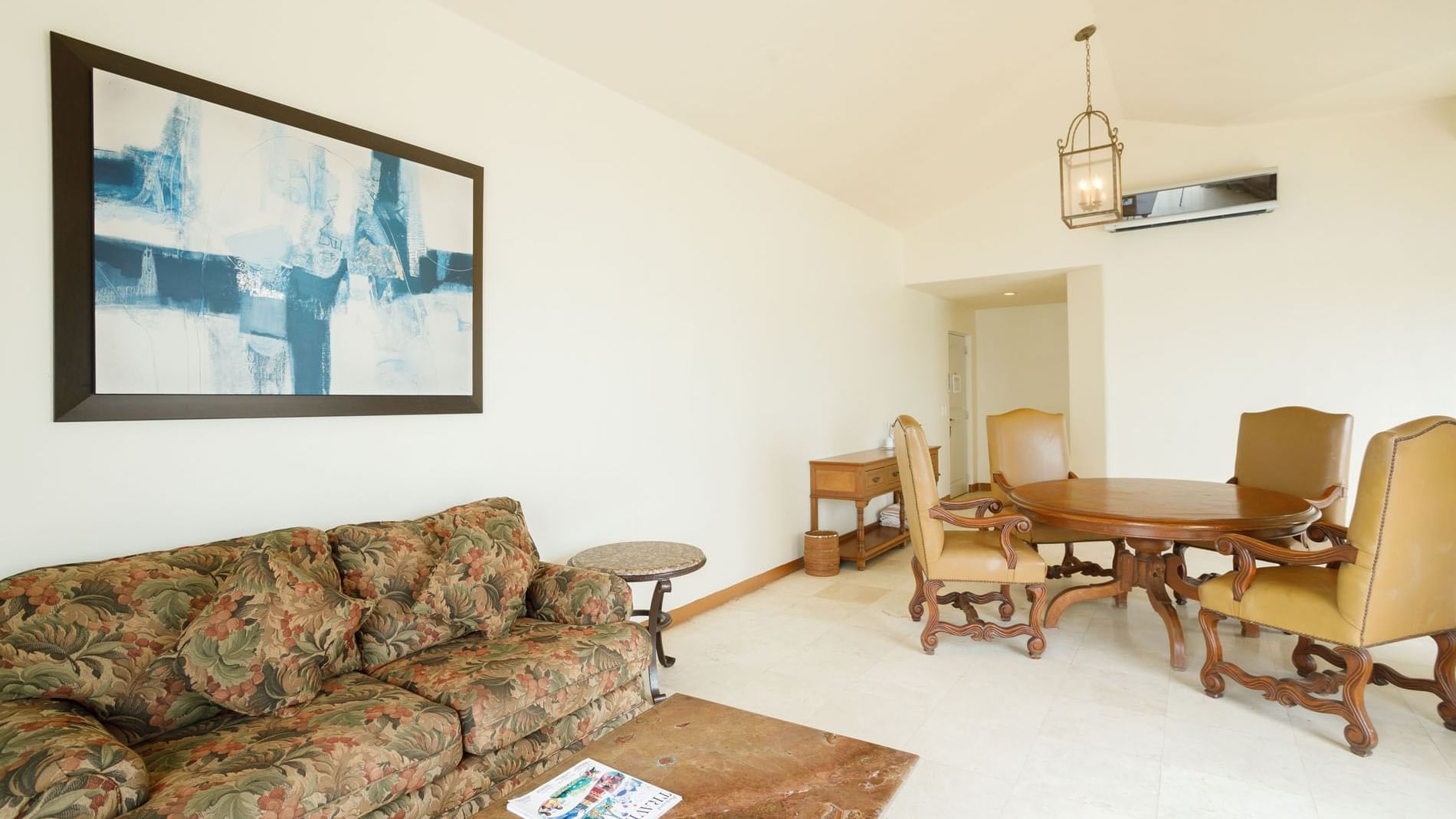 King Governor Suite living room featuring a floral sofa, wooden table, and abstract wall art at Quinta Real Acapulco